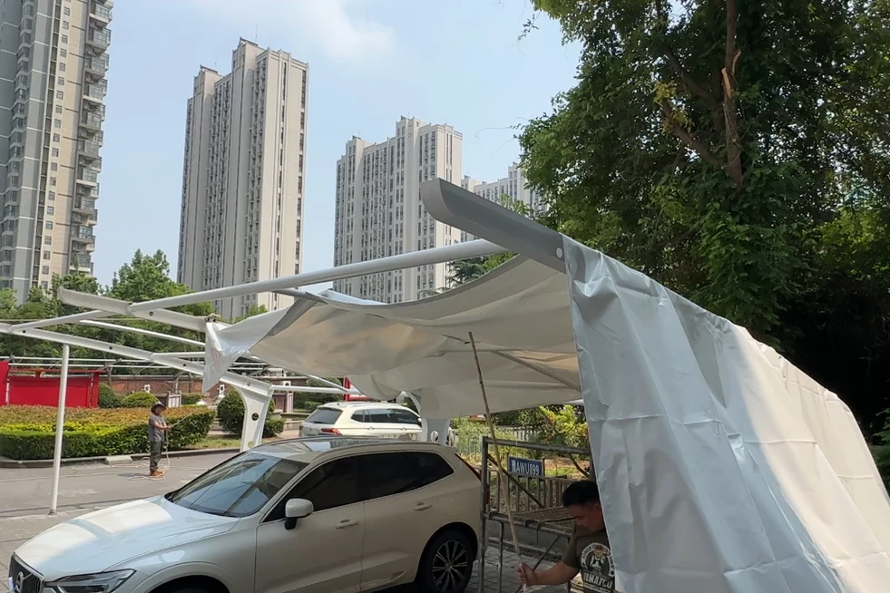 车棚钢架边缘垂下的白色膜材与停车现场实拍
