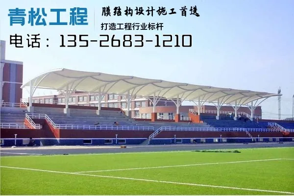A continuous membrane roof covering tiered spectator seating beside a sports field