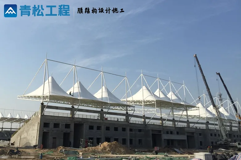 Construction view outside the stand, showing peaked membranes and lifting equipment
