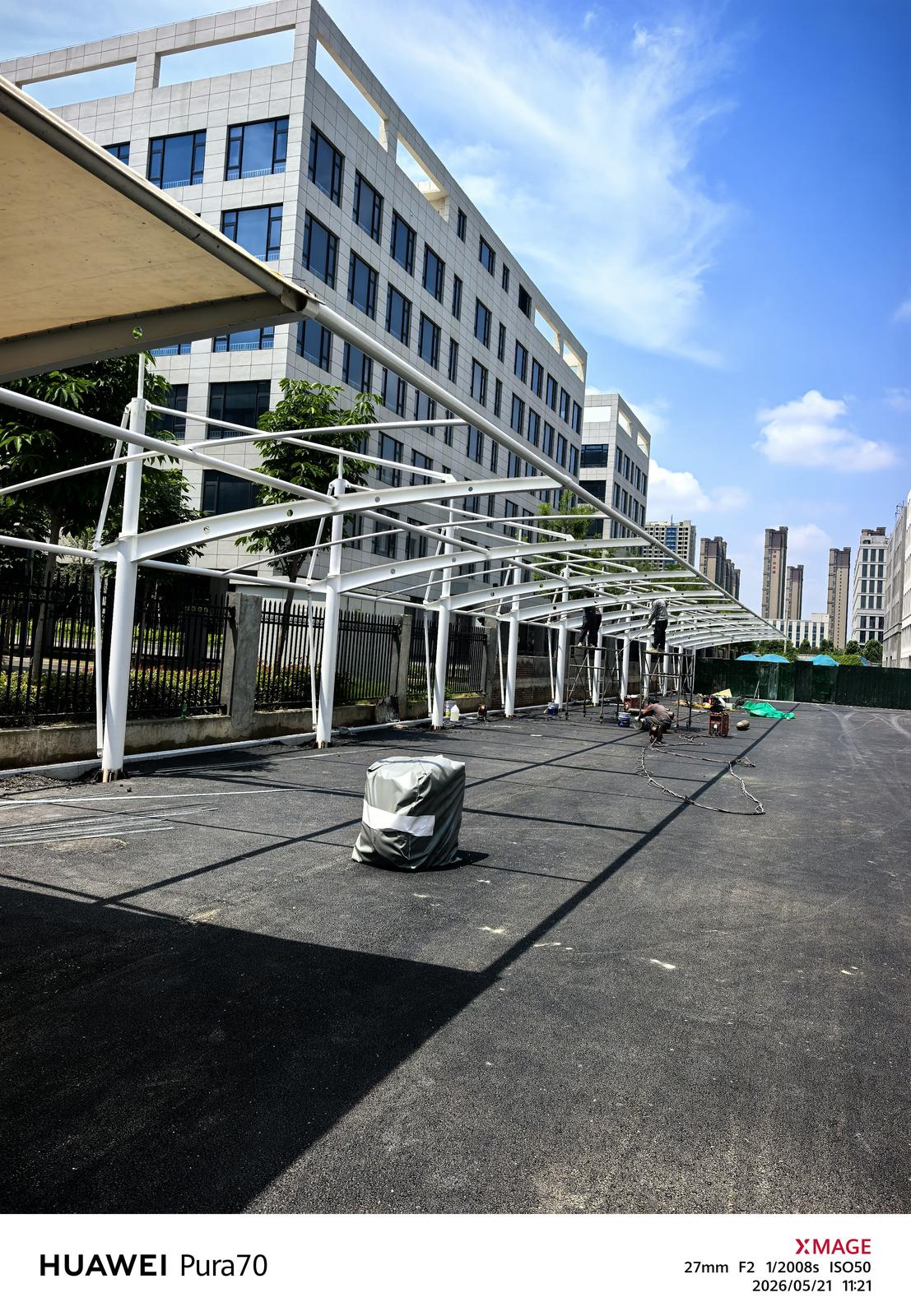 沿建筑立面延伸的拉杆式车棚施工现场