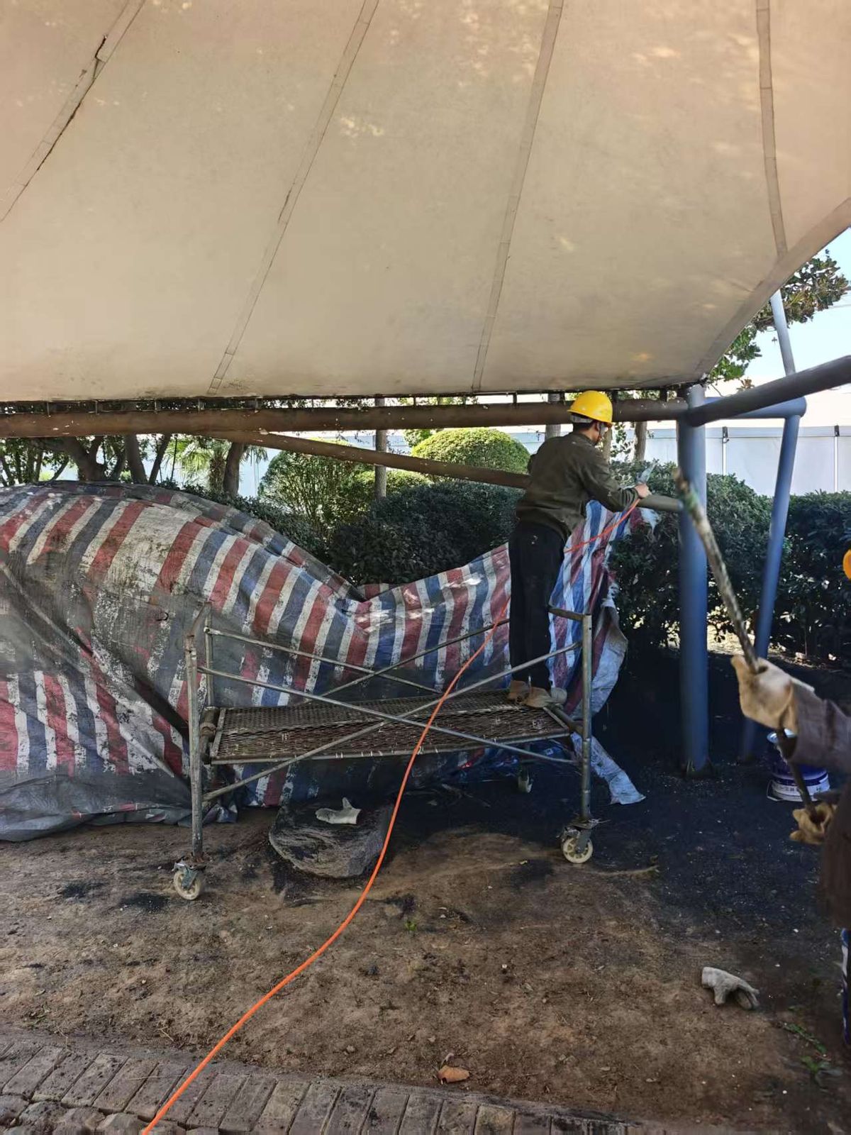 惠济区车棚翻新现场人员处理棚下钢构件表面