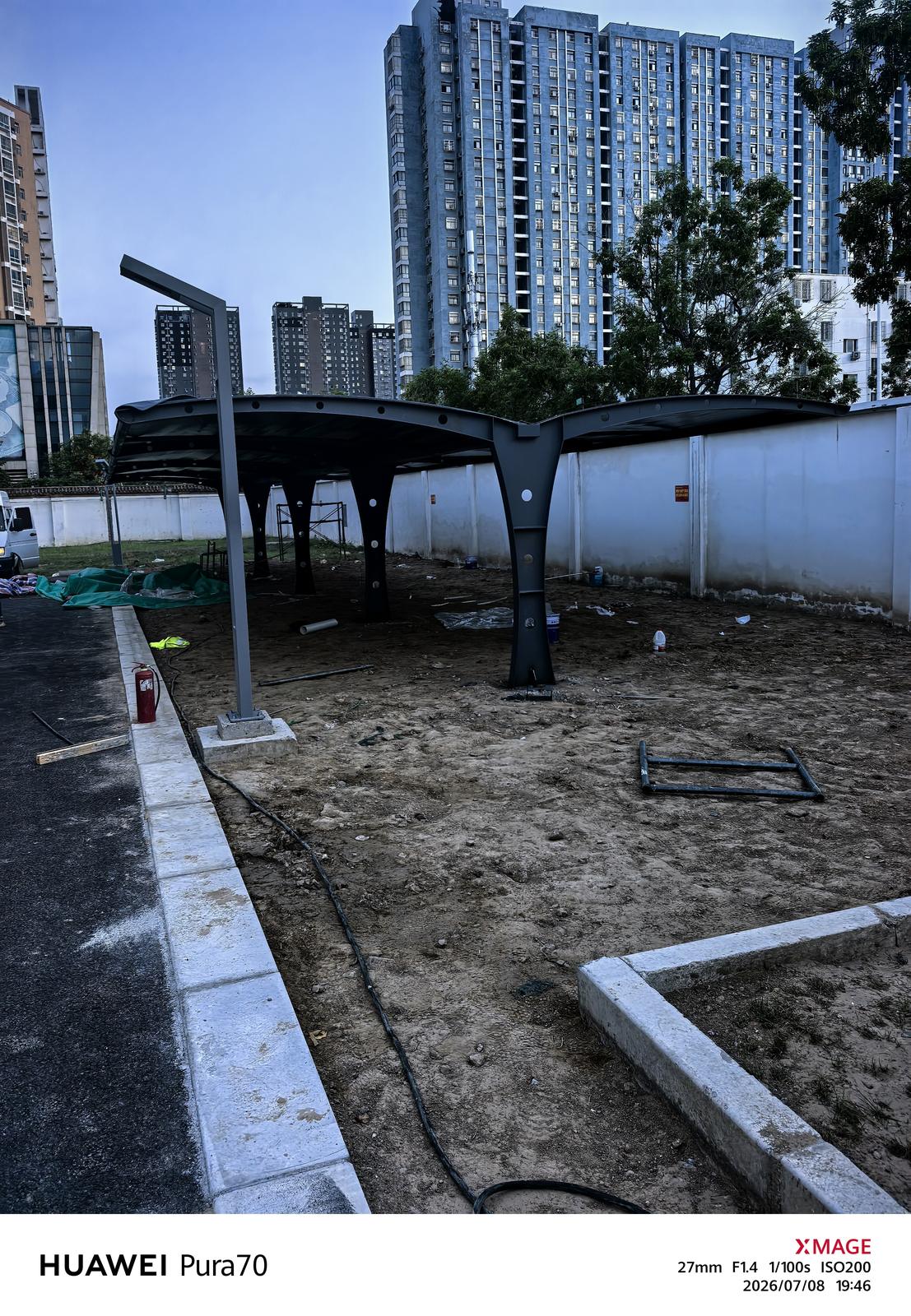 围墙与高层建筑旁正在施工的双挑电动车棚