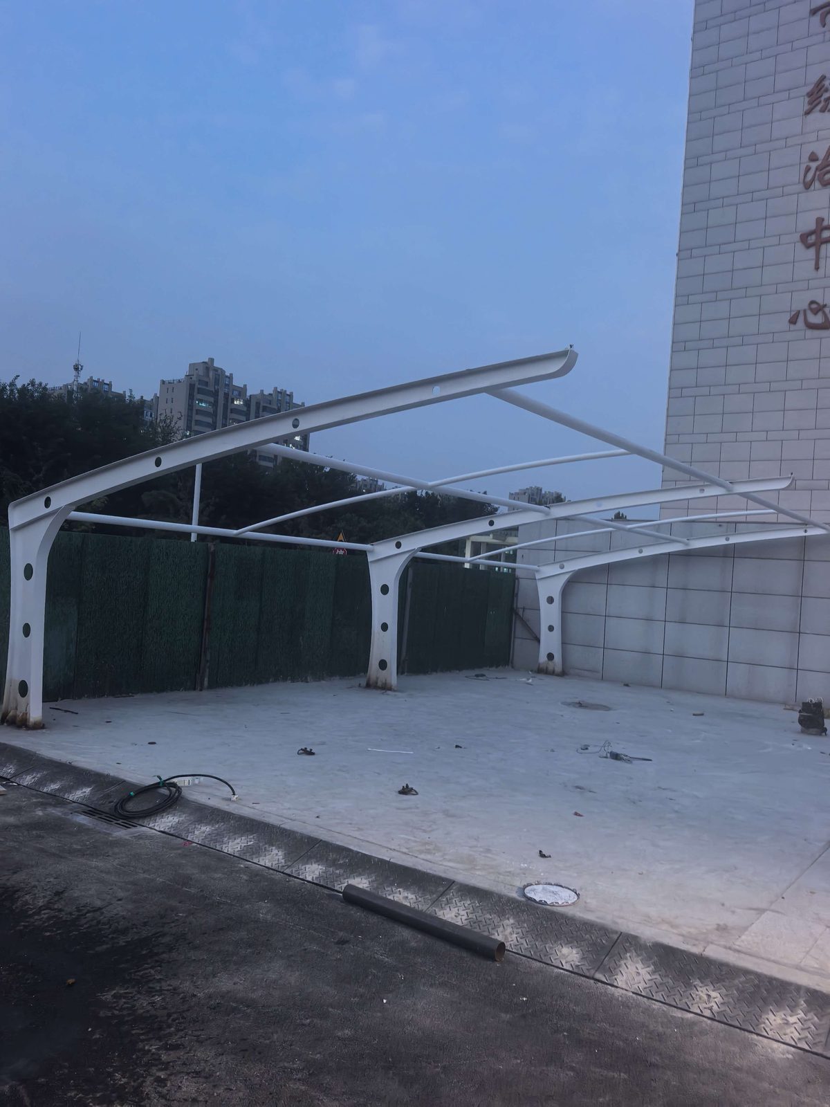 建筑旁尚未铺膜的白色7字型车棚骨架