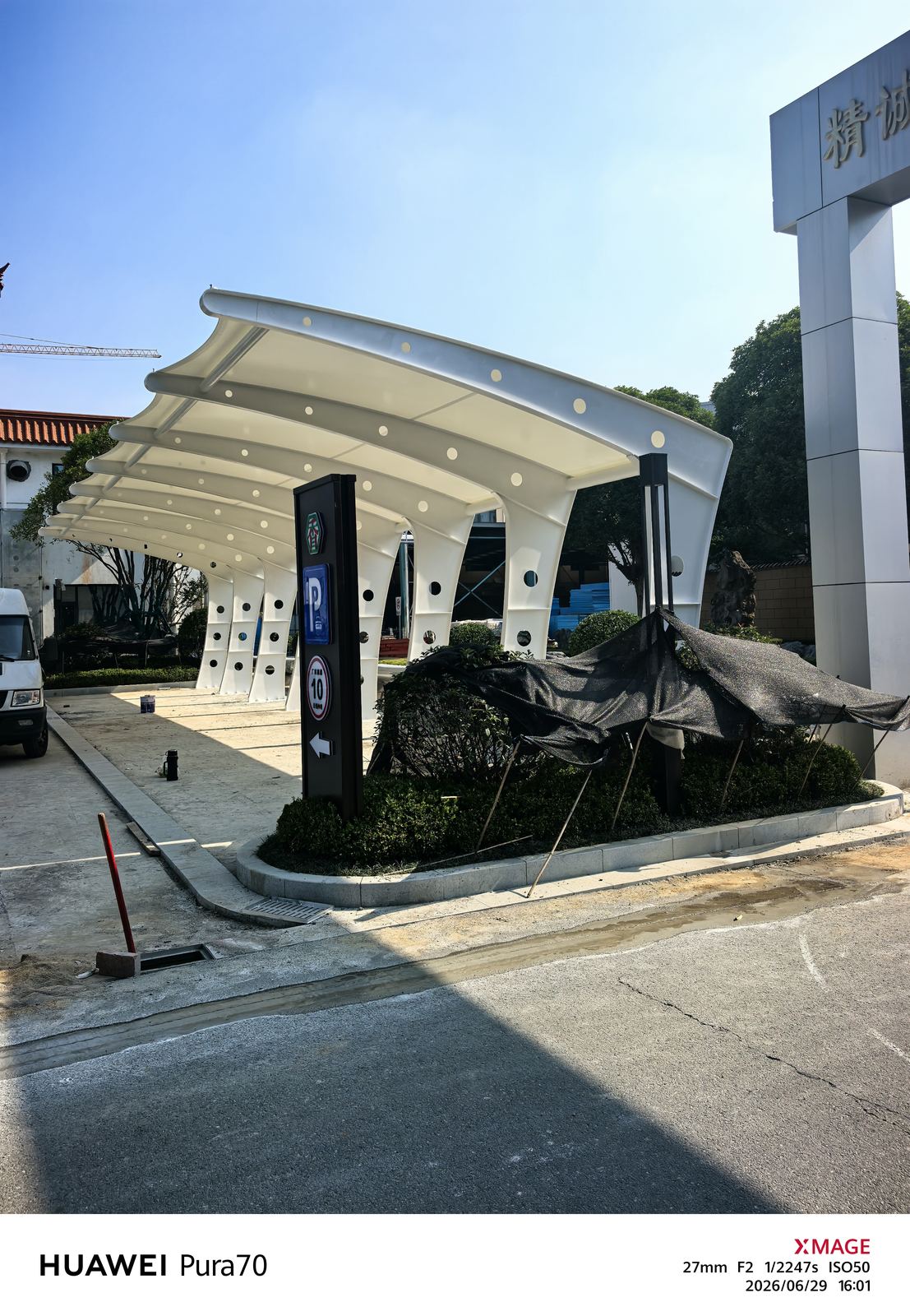 厂区绿化和景观石旁的膜结构车棚端部