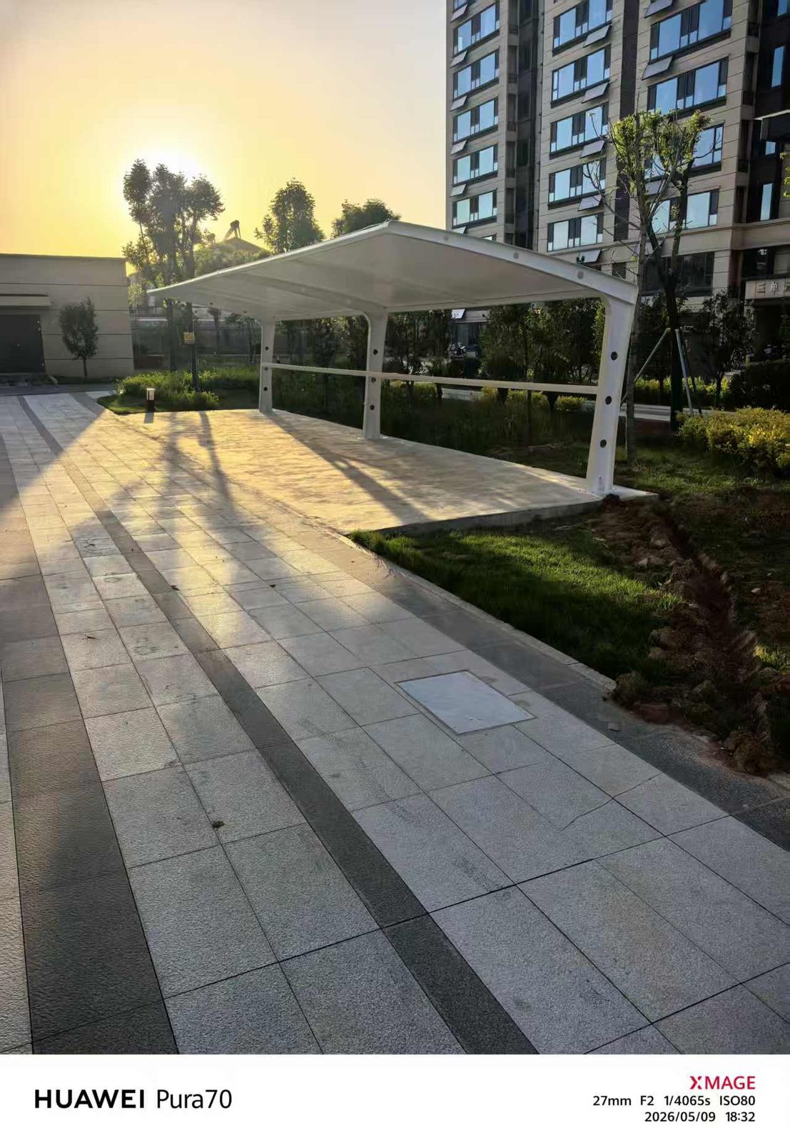 夕阳下住宅步道旁的电动车棚与长条投影