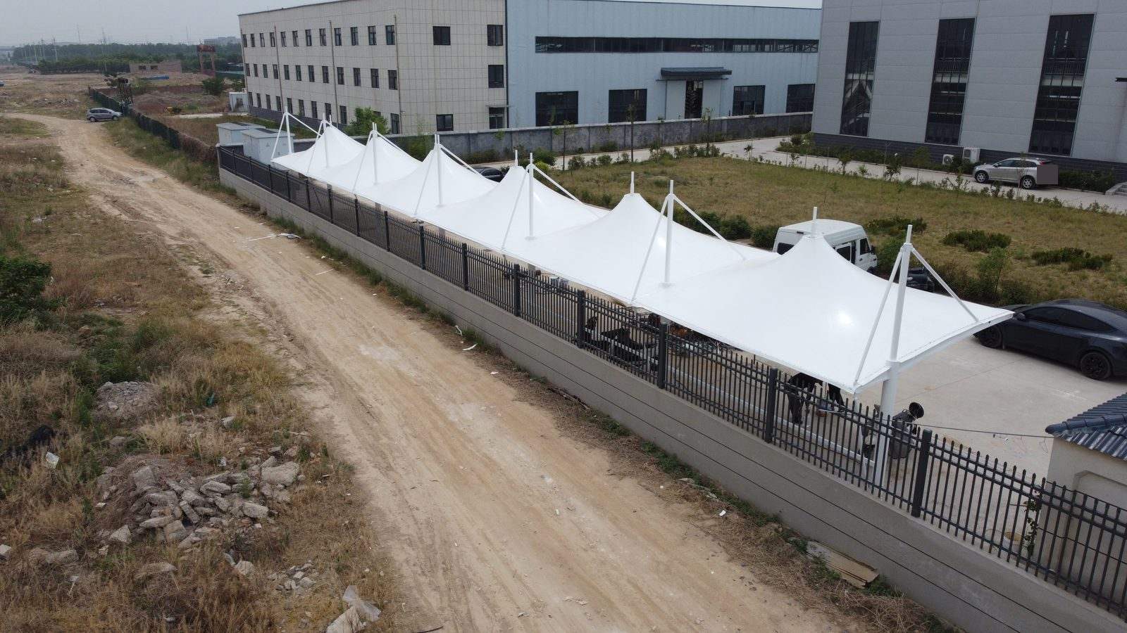 郑州荥阳冒顶式膜结构停车棚斜向航拍全景,连续膜峰沿围栏布置