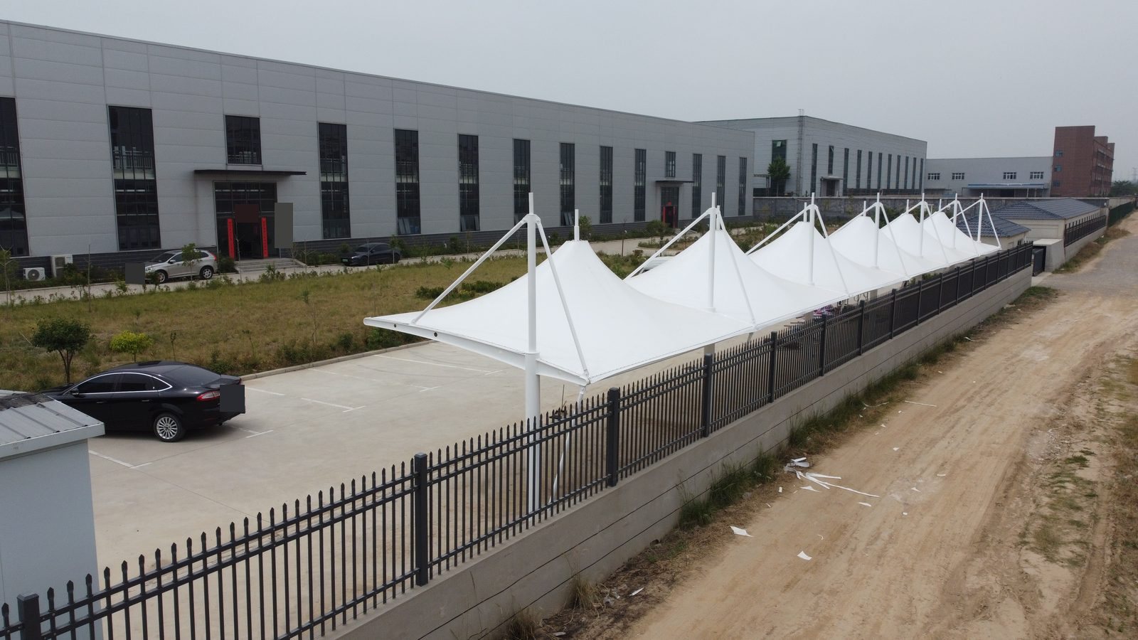郑州荥阳冒顶式膜结构停车棚相反方向侧斜视,展示立柱与斜拉杆