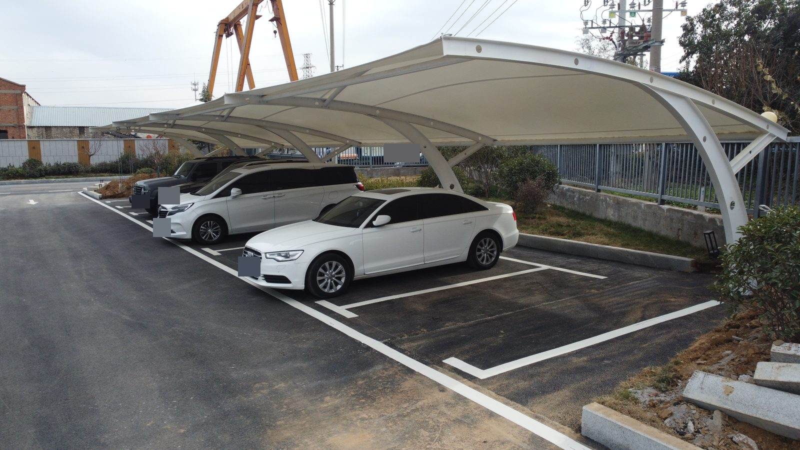 An undulating membrane roof and curved supports cover a row of parking bays. Xingyang, Zhengzhou, Henan, China